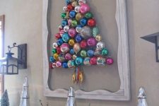 a colorful Christmas tree composed of ornaments attached to the wall and with a frame around for a chic look