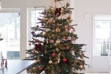 a colorful Christmas tree decorated with gold and red ornaments, lights and bows is a bold and chic idea