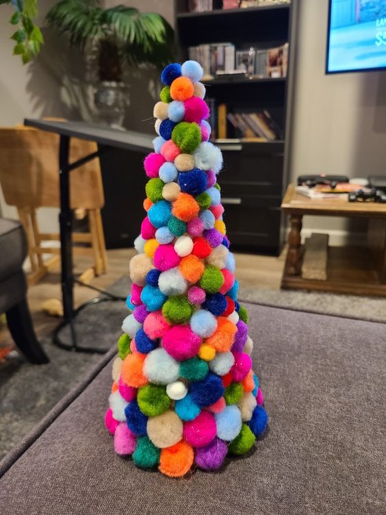 A colorful pompom cone shaped Christmas tree is a nice decoration for any Christmas space