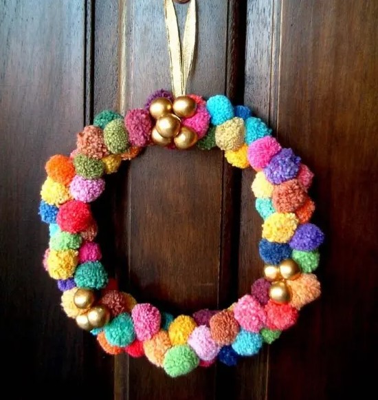 a colorful pompom wreath with gold ornnaments is a nice idea for Christmas or New Year and it will bring much color