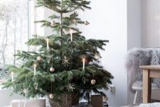 a delicate modern Scandinavian Christmas tree in a basket, with a bit of gold ornaments and some candles is a chic idea to rock
