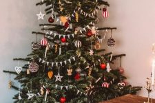 a lovely bright Scandinavian Christmas tree decorated with yellow and red ornaments, stripes, apples, faux candles and lights