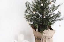 a minimalist Nordic tabletop Christmas tree decorated with wooden beads and wrapped into kraft paper is simple but cool