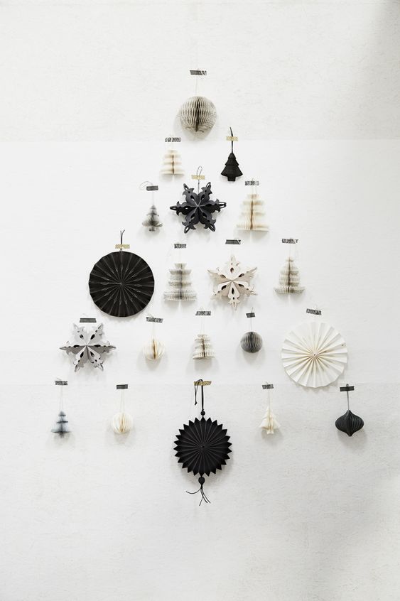 a minimalist wall-mounted Christmas tree composed of black and white cardboard and paper ornaments