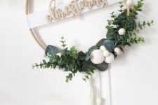 a modern Christmas wreath of an embroidery hoop, greenery, white pompoms and white tassels