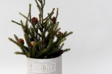 a modern small Christmas tree with pinecones in a planter is a cool and very natural-looking decoration