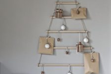 a modern wall-mounted Christmas tree of sticks hanging, with ornaments and gifts, is a cool solution