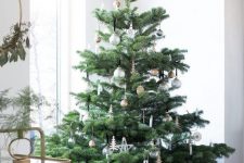 a neutral Scandinavian Christmas tree with white and silver ornaments and some plywood tree ornaments