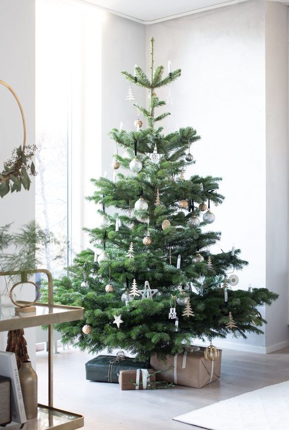a neutral Scandinavian Christmas tree with white and silver ornaments and some plywood tree ornaments