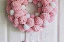 a pink and white pompom Christmas wreath with matching tassels is a cool and fun decor idea for the holidays