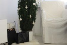 a potted Christmas tree decorated with lights, white baubles and stars is a lovely minimalist meets Scandi decor idea