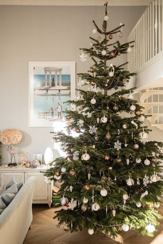 a pretty Scandinavian Christmas tree decorated with copper and white ornaments, snowflakes, lights and other decor