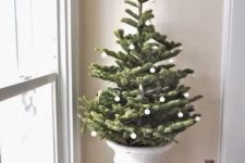 a refined Christmas tree in an urn, with small white ornaments is a very elegant and cool idea