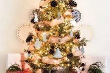 a rustic tabletop Christmas tree with lights, pinecones, little paper and clay ornaments and a basket as a base