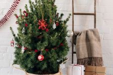 a small Christmas tree in a basket and with silver and red ornaments is a cool and catchy decoration