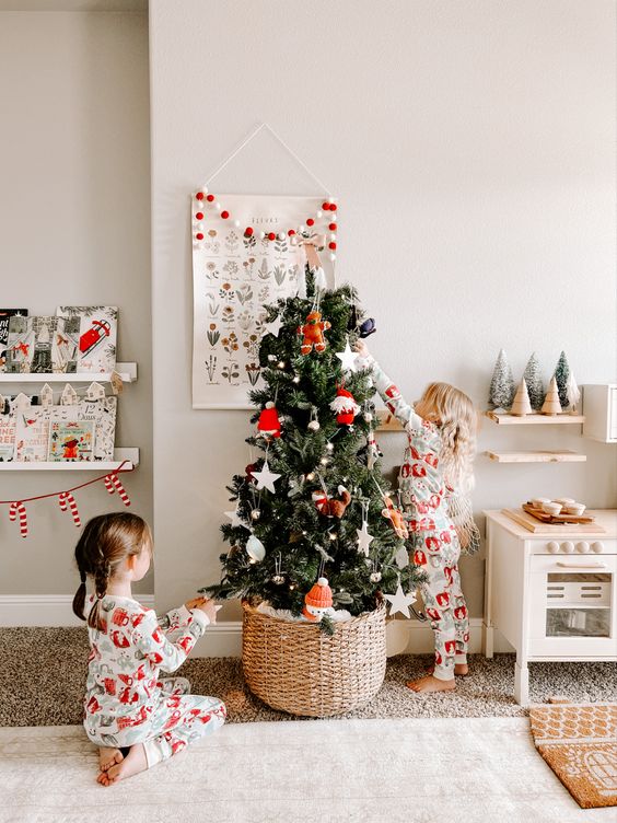 a small Christmas tree in a playroom, placed in a basket and decorated with little toys is a very fun and cool idea