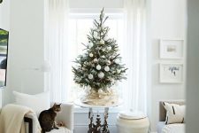 a small Christmas tree with white ornaments and lights is a cool solution for a neutral holiday space