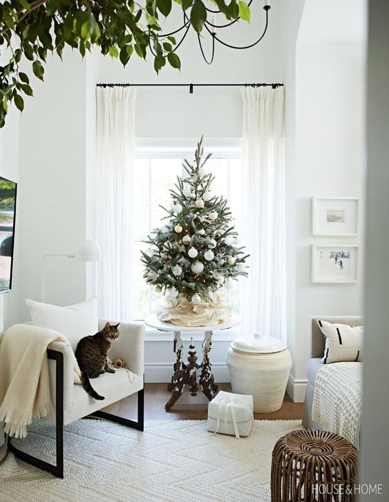 a small Christmas tree with white ornaments and lights is a cool solution for a neutral holiday space