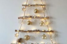 a wall-mounted Christmas tree made of branches and rope, with lights, ornaments and snowflakes is a cool idea