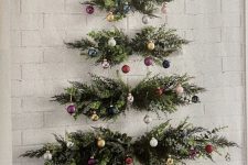 a wall-mounted Christmas tree of evergreens and greenery and colorful ornaments attached