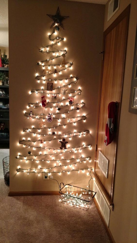 A wall mounted Christmas tree of lights and with ornaments and decor is a cool and bold decor idea for the holidays