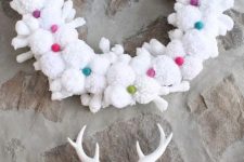 a white pompom and snowflake wreath with colorful mini pompoms is a cool Christmas decoration