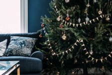 an elegant Christmas tree with red and gold ornaments, lights and banners is a cool Scandi decor idea