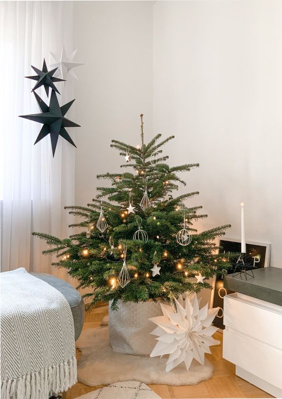 an elegant small Christmas tree in a basket, with lights, white star and himmeli ornaments for the holidays
