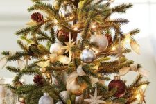 an elegant tabletop Christmas tree with lights, silver, gold and brown ornaments, burlap bows and pinecones