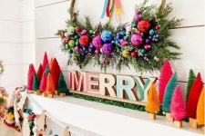 an extra bold Christmas mantel with bright bottle brush trees, letters, a wreath with ornaments and greenery, felt balls and wooden Christmas trees