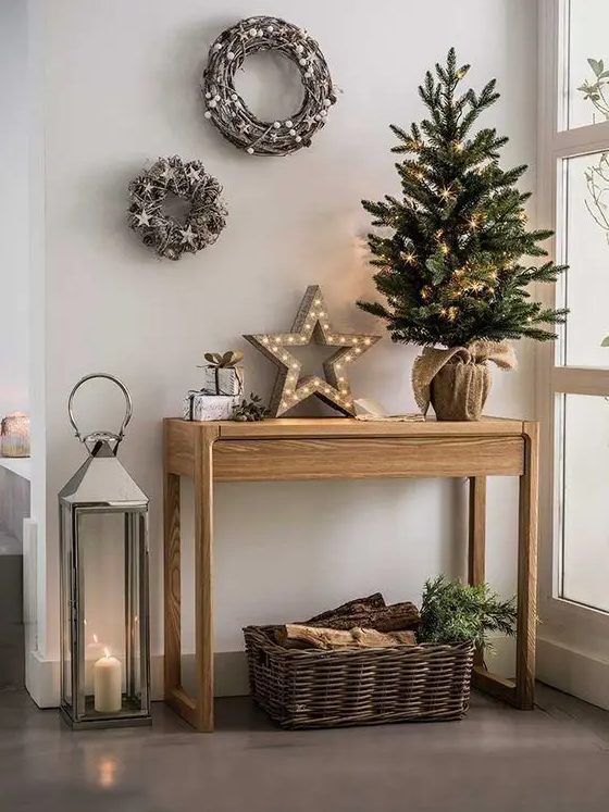 beautiful rustic Christmas decor with a tree in burlap, a basket with firewood, a marquee star light, vine wreaths with stars and pinecones