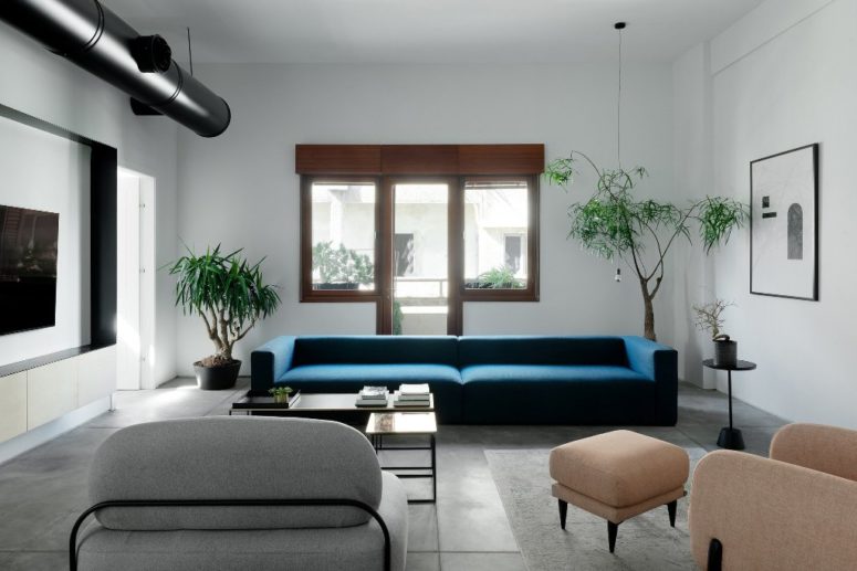The living room is done with a stylized metal pipe, neutral coomfy furniture and a bold blue sofa