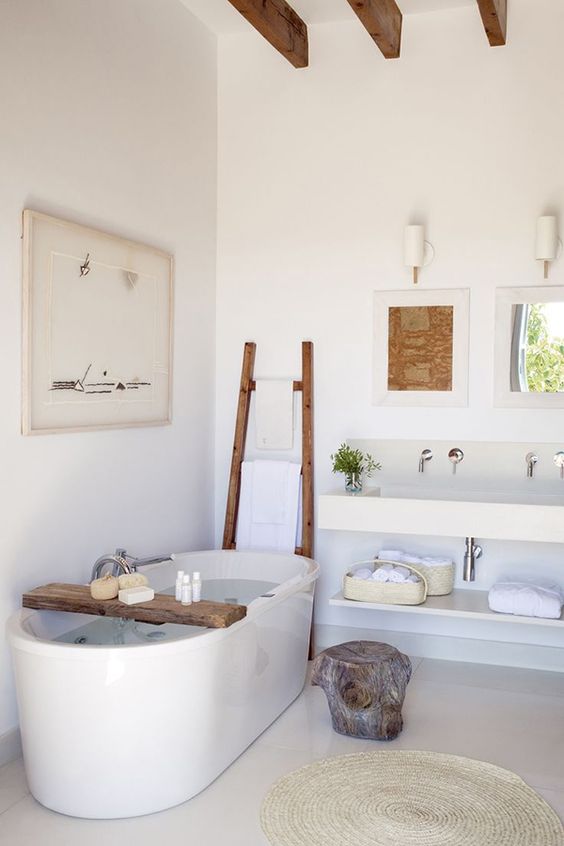 A neutral bathroom with wooden touches and a free standing bathtub plus some rough wood accessories