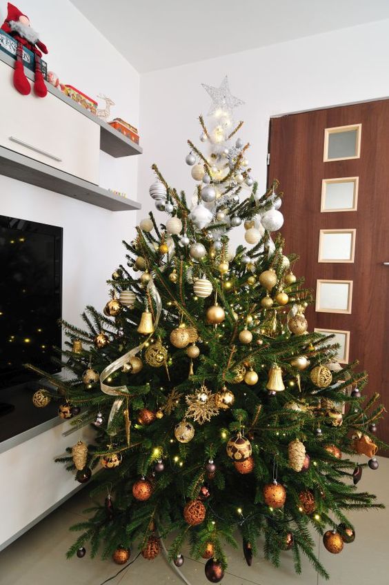 a beautiful and luxurious ombre silver to gold and copper Christmas tree with lights and a star on top looks very chic
