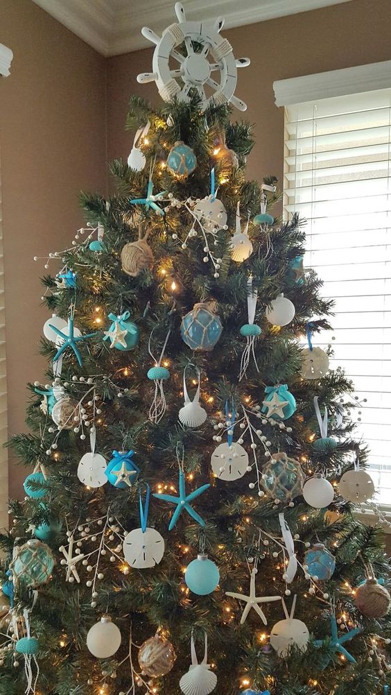 a bold beach Christmas tree with blue and white ornaments styled as floats and shells plus twine balls