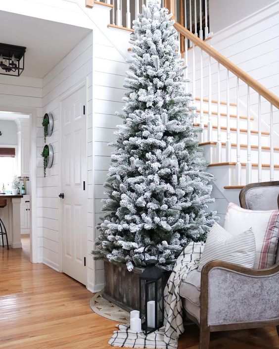 a flocked Christmas tree with no decor in a crate is a great idea for any entryway, add some candles around
