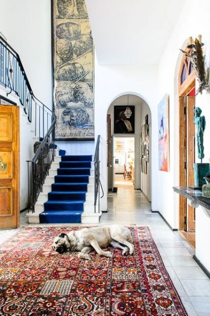 a very eclectic entryway with an oversized vintage artwork balanced with a large boho chic rug