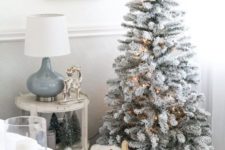 04 a cozy neutral space with a flocked Christmas tree with lights, a basket with fur and skis and tinsel trees