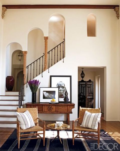 neutral textural walls, wrought railings, little pillars and wooden furniture make up a cool MEditerranean space