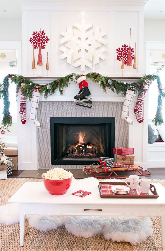 a beautiful contemporary living room dotted with reds, snowflakes, gifts, stockings and red ornaments