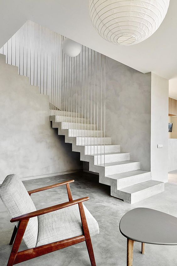 a minimalist entryway with a concrete staircase and timelessly elegant furniture