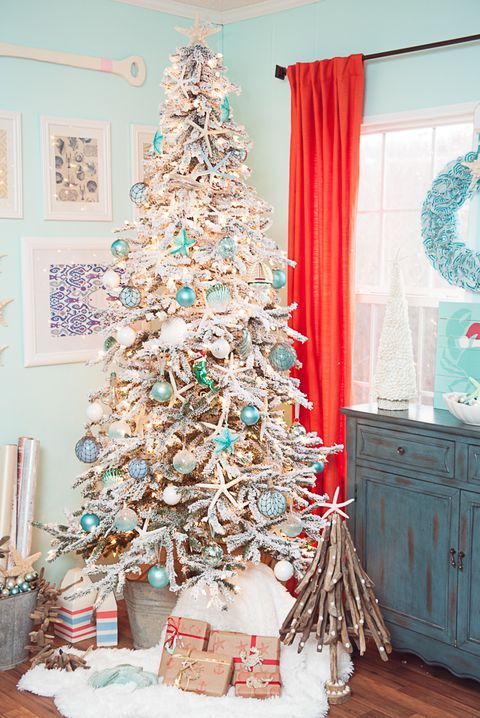 A flocked Christmas tree with float like ornaments, lights, star fish features strong coastal vibes