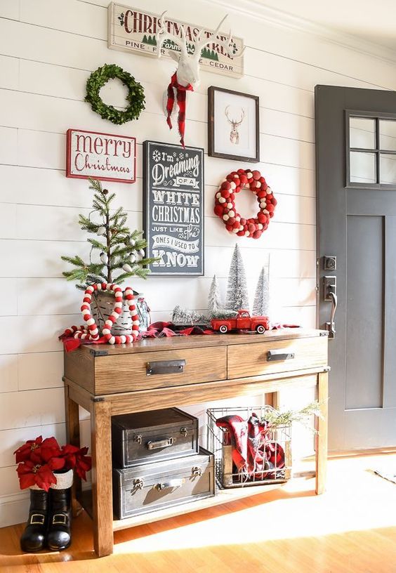 a gorgeous gallery wall for holidays with a couple of wreaths, signs and a fake deer head for your entryway