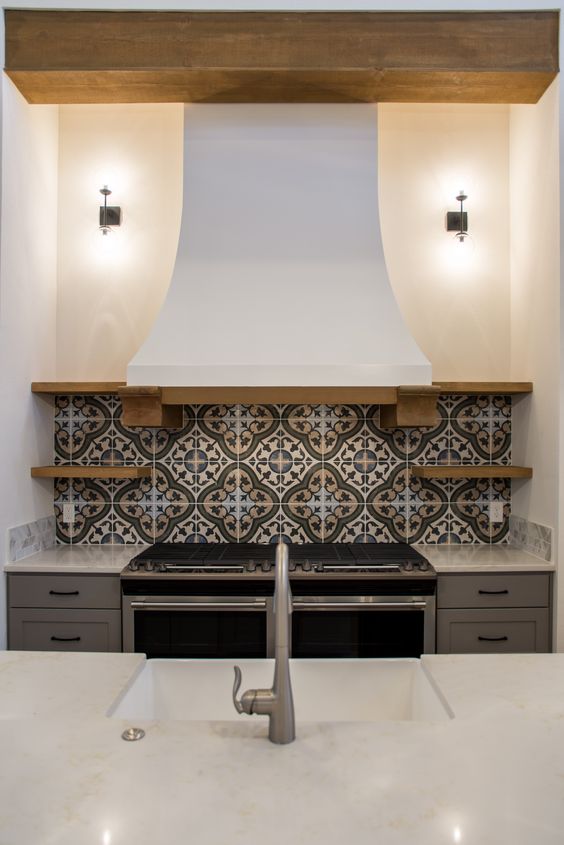 a mosaic tile backsplash and a vintage kitchen hood bring Mediterranean vibes to the space