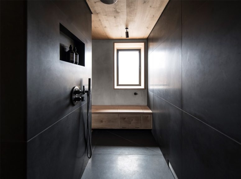 The master bathroom is done with black tiles and concrete and wood to tie it up with other spaces