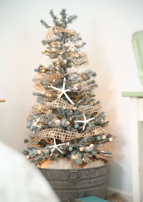 A flocked Christmas tree decorated with star fish, nets and beach colored pompoms and lights