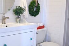07 a single greenery Christmas wreath with a star and a red tray for toilet paper will make your bathroom feel holiday-like