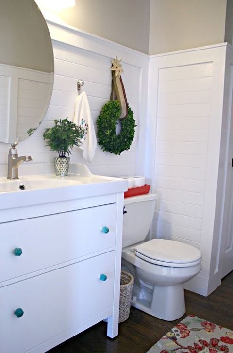 a single greenery Christmas wreath with a star and a red tray for toilet paper will make your bathroom feel holiday-like