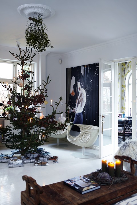 The living room is done with an oversized artwork, very catchy chairs and a large Christmas tree with ornaments and hanging greenery
