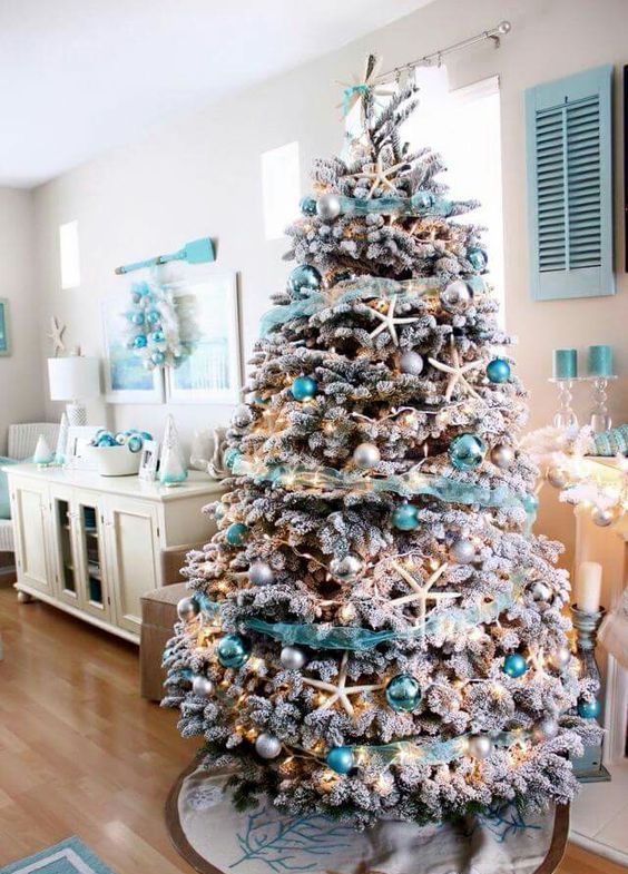 a flocked Christmas tree with star fish, silver and turquoise ornaments and turquoise garlands